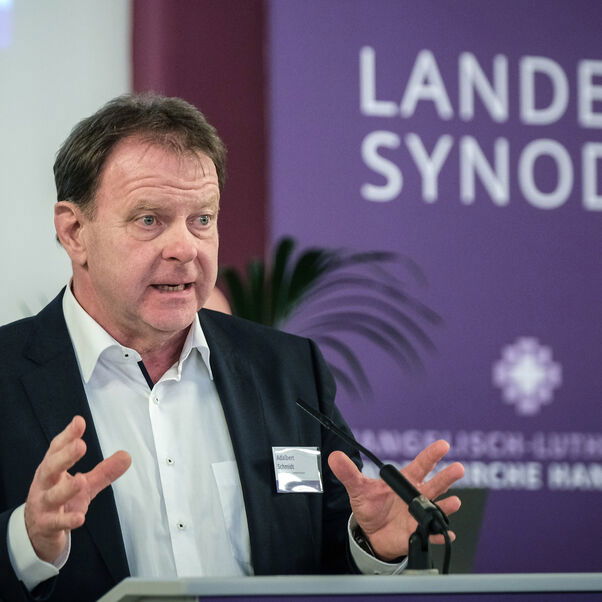 Eine männlich lesbare Person an einem Rednerpult