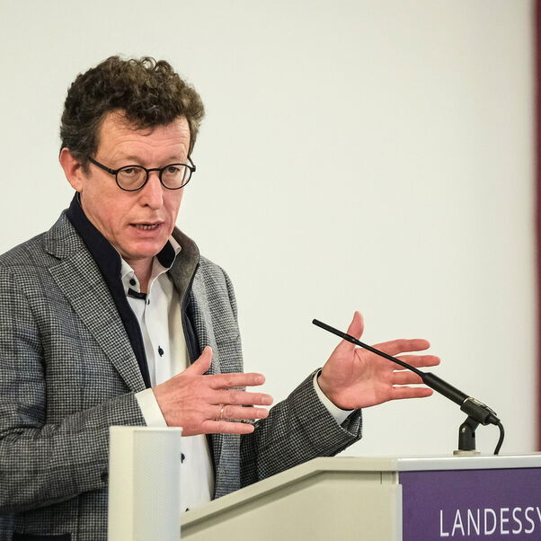 Eine männlich lesbare Person an einem Rednerpult