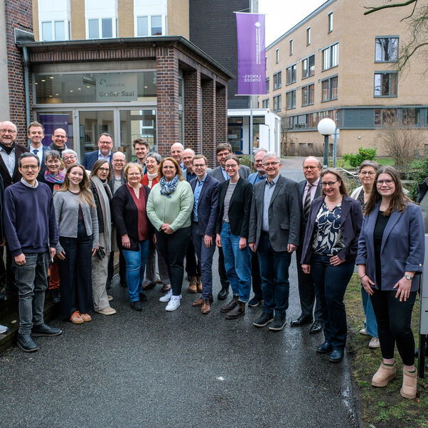 Mehrere Personen stehen zusammen und lächeln in die Kamera