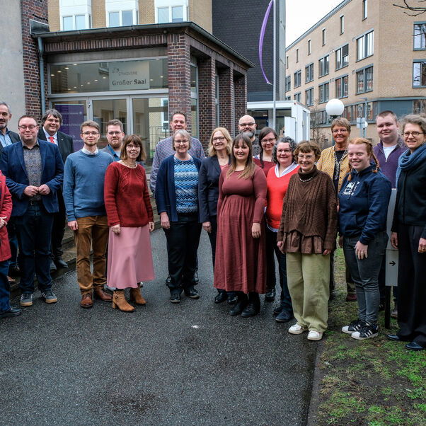 Mehrere Personen stehen zusammen und lächeln in die Kamera