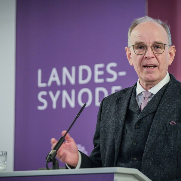 Eine männlich lesbare Person an einem Rednerpult