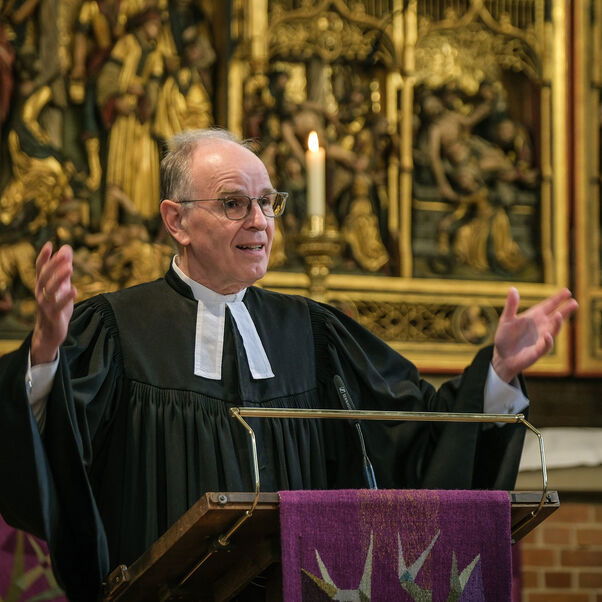 Eine männlich lesbare Person an einer Kanzel vor einem Altar