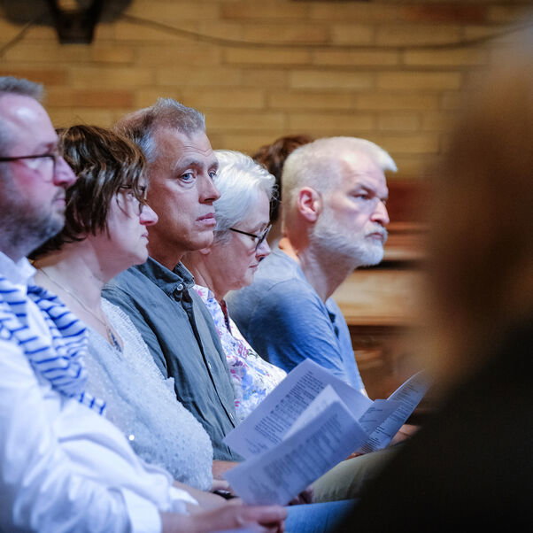 Mehrere Personen sitzen in einer Kirchenbank