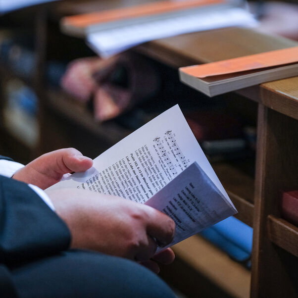 Eine Person hält einen Liederzettel in den Händen