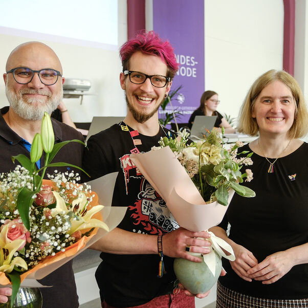 Drei Personen mit Blumensträußen in der Hand