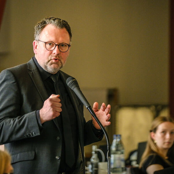 Eine männlich lesbare Person an einem Mikrofon