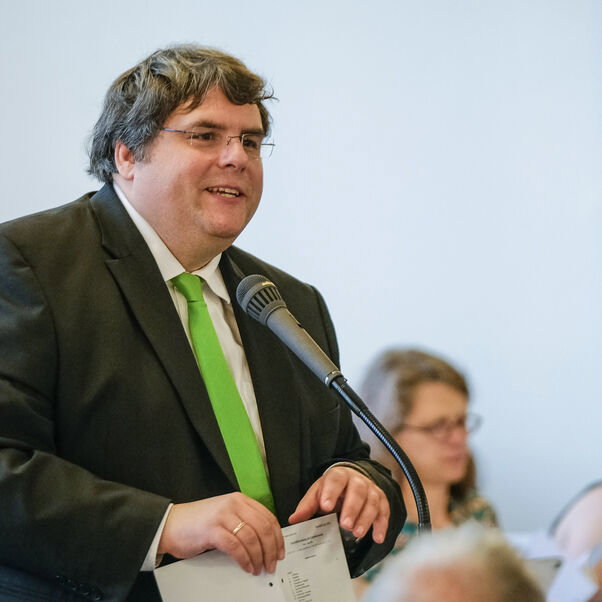 Eine männlich lesbare Person an einem Mikrofon