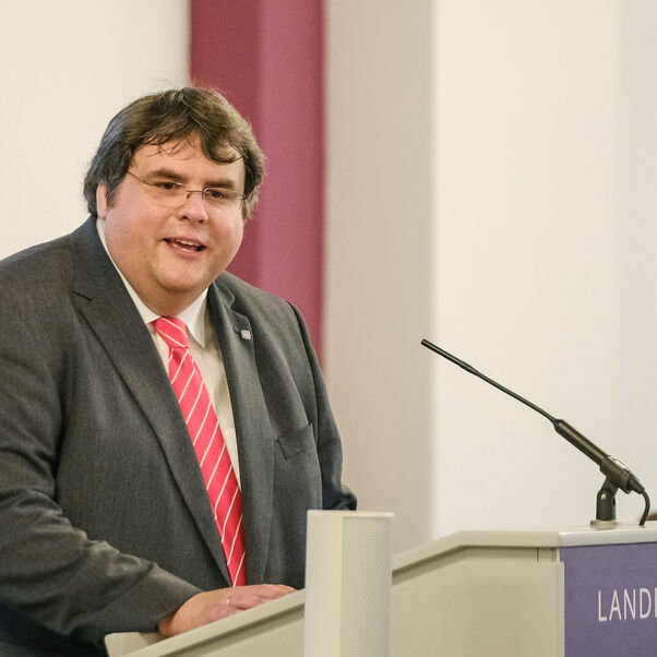 Eine männlich lesbare Person an einem Rednerpult