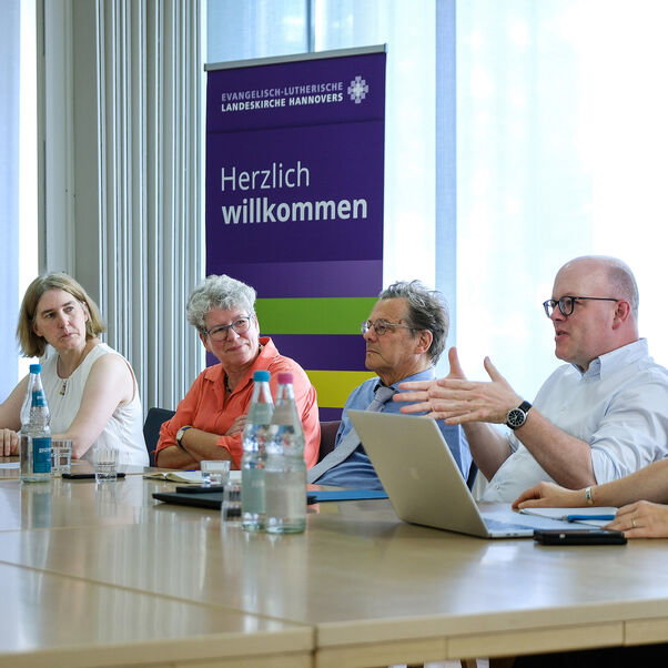 Mehrere Personen sitzen an einer Tischreihe