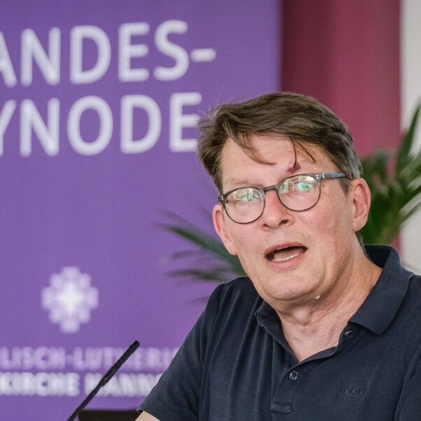 Eine männlich lesbare Person an einem Rednerpult