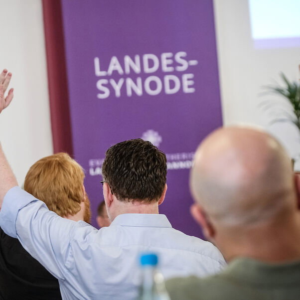 Mehrere Personen heben die Hand zur Abstimmung