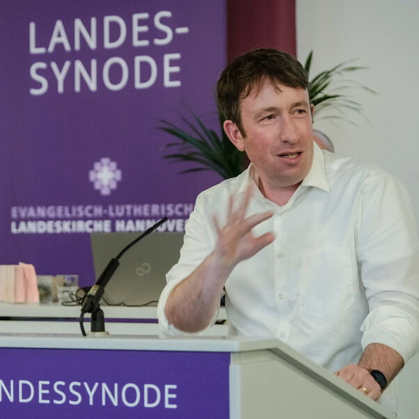 Eine männlich lesbare Person an einem Rednerpult