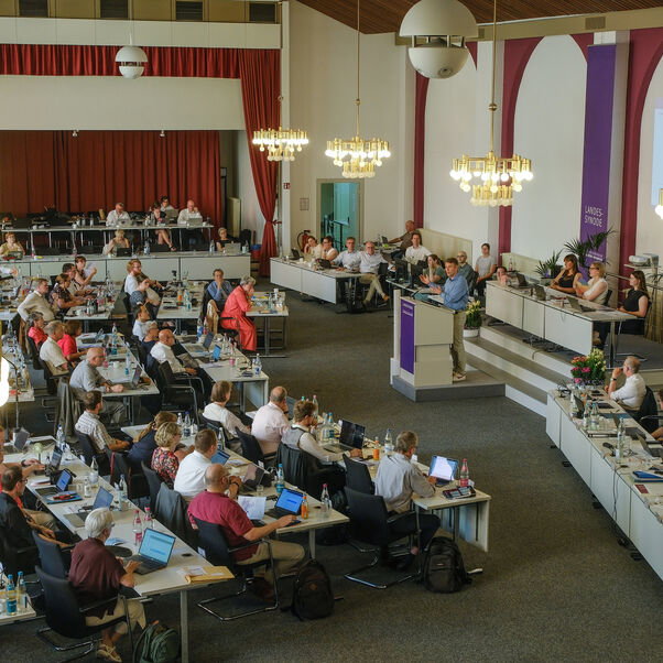 Viele Personen an Tischen in einem Sitzungssaal