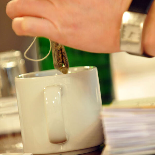 Teebeutel wird aus Tasse gehoben