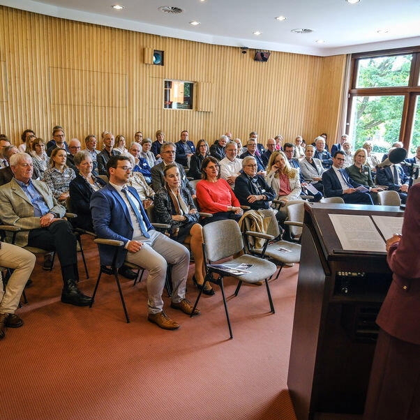 Die Direktorin der Evangelischen Akademie Loccum, Prof. Dr. Julia Koll, spricht vor einem gut besuchten Plenum in einem Tagungsraum der Akademie. 