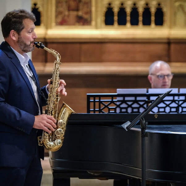 Im Bild sind ein Saxophon-Spieler (vorne) und ein Klavierspieler an einem Flügel (hinten). Beide stehen in der Klosterkirche Loccum. 