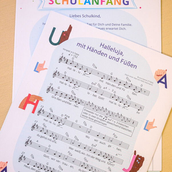 Das gefaltete Plakat mit dem Fingeralphabet enthält ein Grußwort von Landesbischof Ralf Meister und ein Lied.