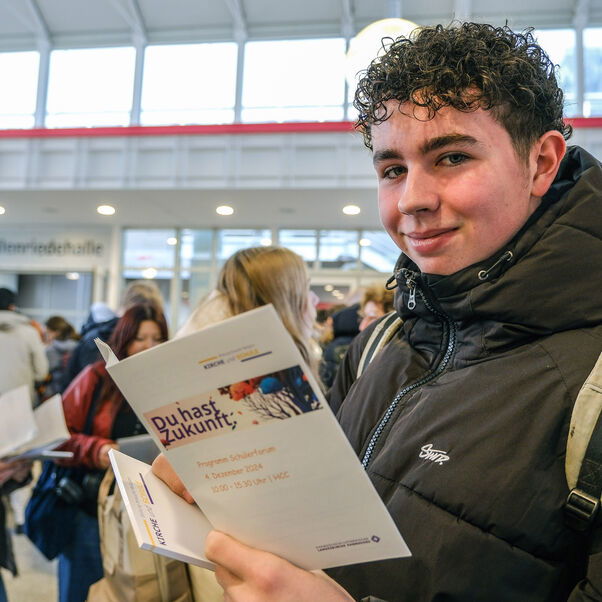 ein Schueler haelt eine Broschuere in der Hand