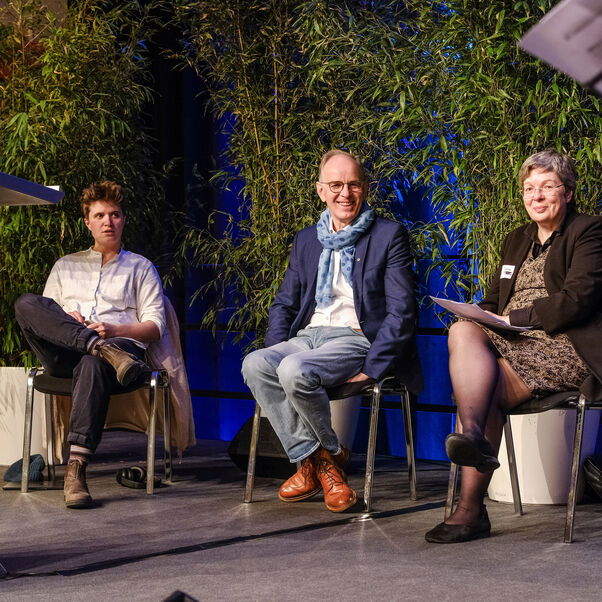 Drei Menschen bei einer Podiumsdiskussion