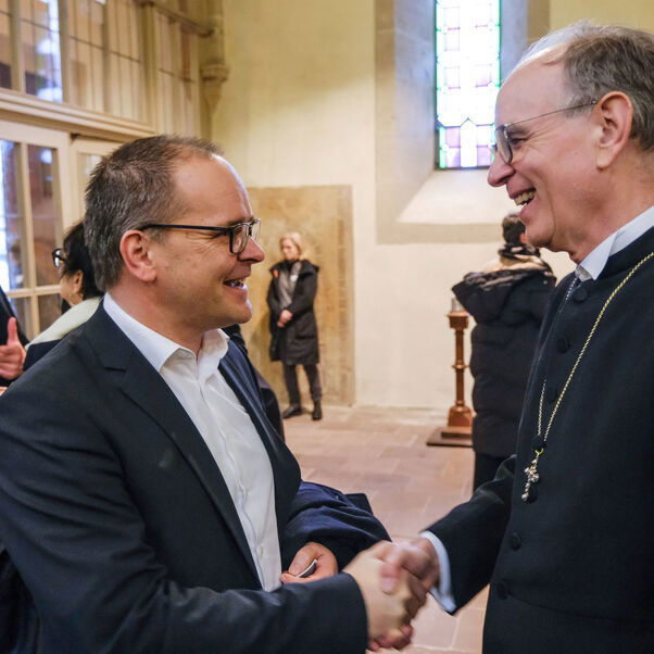 Zwei männlich zu lesende Personen begrüßen sich.