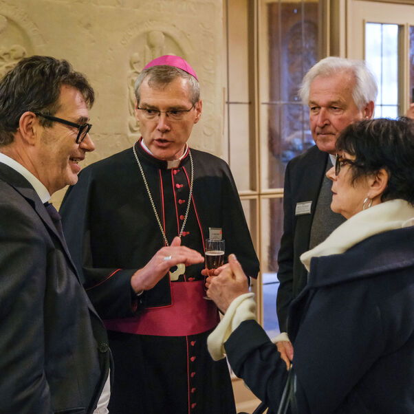 Drei männlich und eine weiblich zu lesende Person im Gespräch.