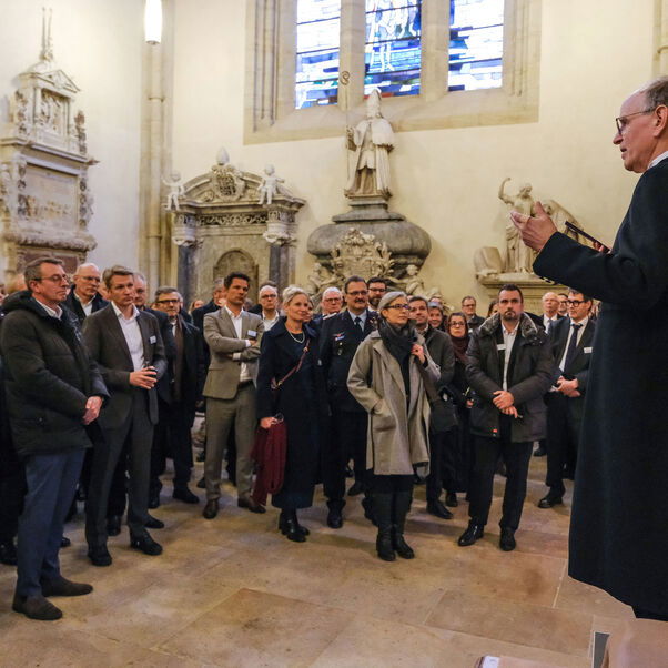 Eine männlich zu lesende Person spricht zu einer größeren Zahl von Personen.