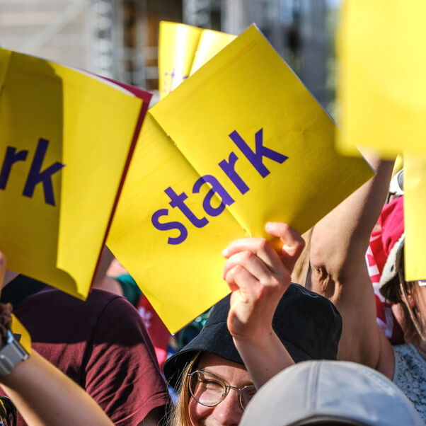 Menschen halten gelbe Schilder mit der Aufschrift "stark" in die Höhe.