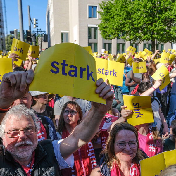 Menschen halten gelbe Schilder mit der Aufschritt "stark" hoch.