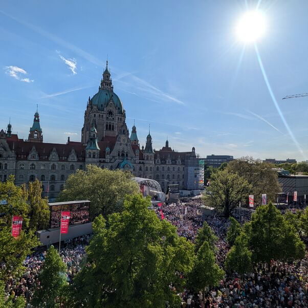 Viele Menschen haben sich bei blauem Himmel und Sonnenschein zu einem Gottesdienst vor dem neuen Rathaus versammelt.