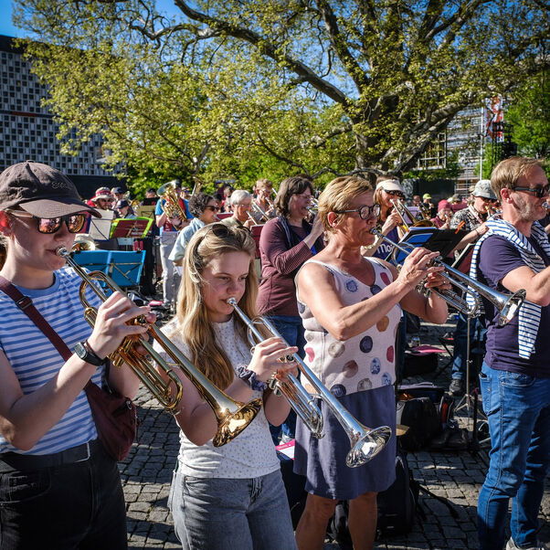 Menschen, die unter freiem Himmel Blasinstrumente spielen.