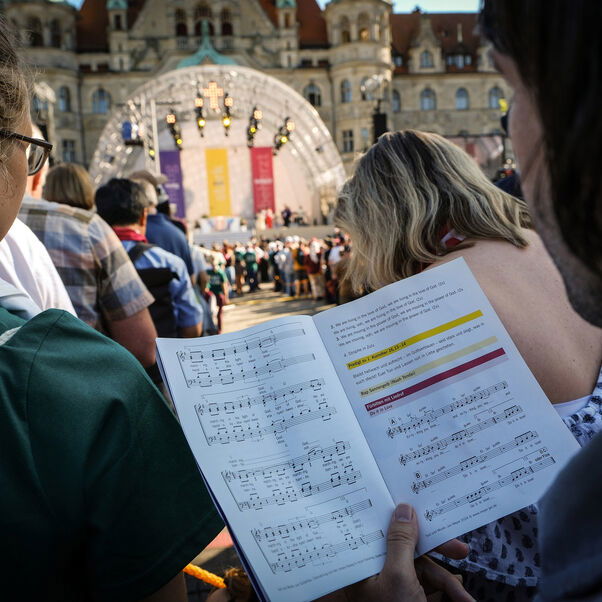 Blick über die Schulter eines Menschen, der in ein Liedblatt schaut.