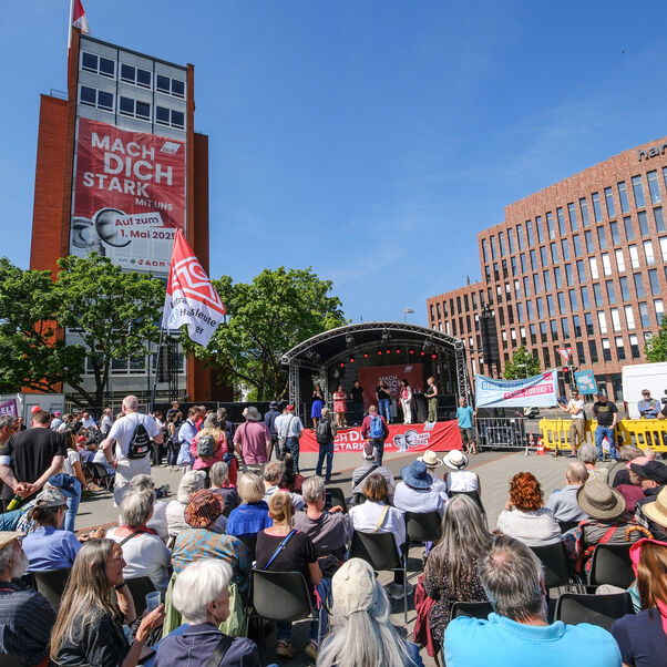 Eine große Gruppe von Menschen steht vor einer Bühne.