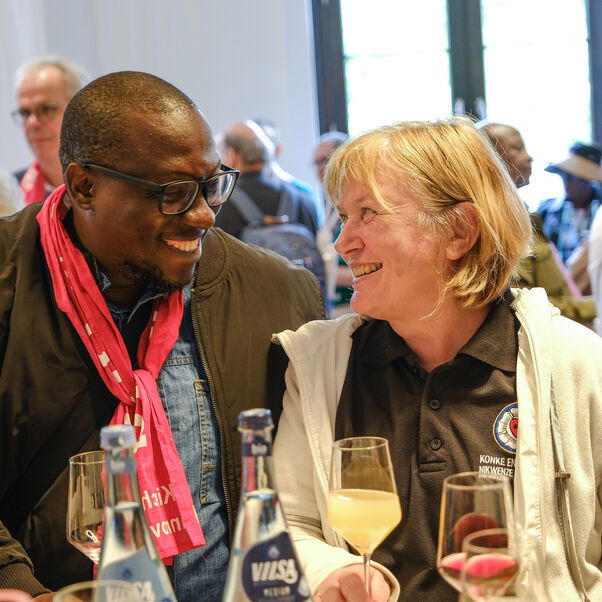 Eine weiblich und eine männlich zu lesende Person unterhalten sich bei einem Empfang.