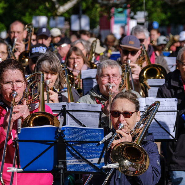 Blechbläserinnen und Blechbläser machen unter freiem Himmel Musik.