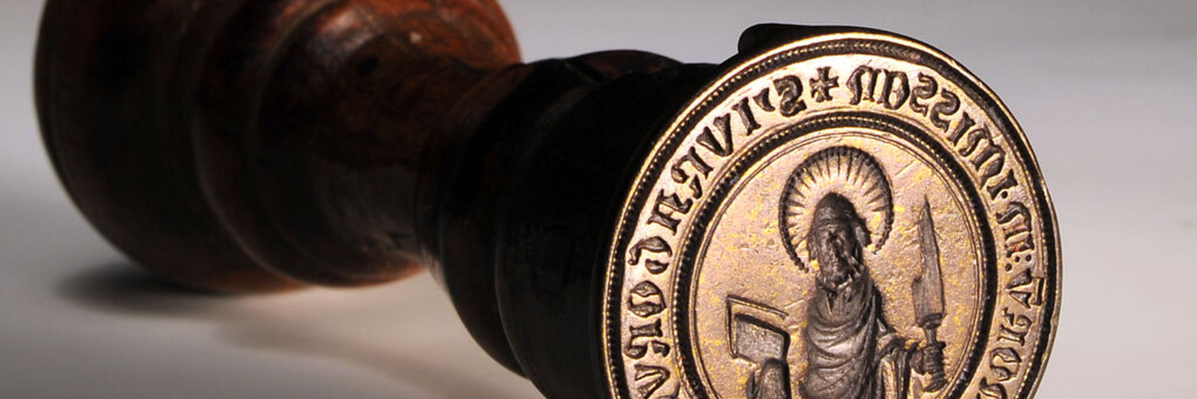 Das Bild zeigt den Siegelstempel der Landeskirche Hannovers mit braunem Holzgriff.