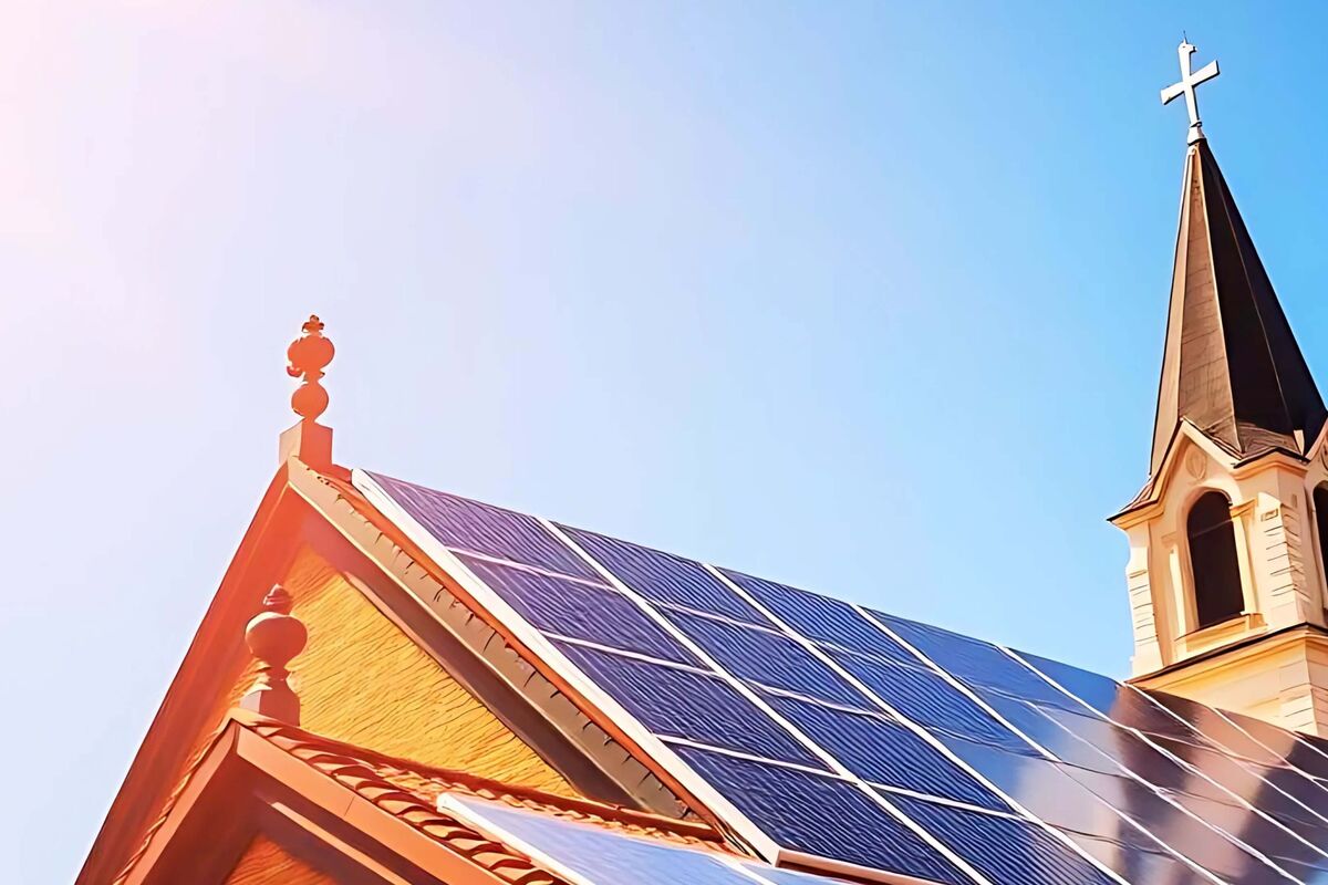 Kirchendach mit Photovoltaik und Kirchturm im Sonnenlicht – Symbol für erneuerbare Energien und Schöpfungsbewahrung.