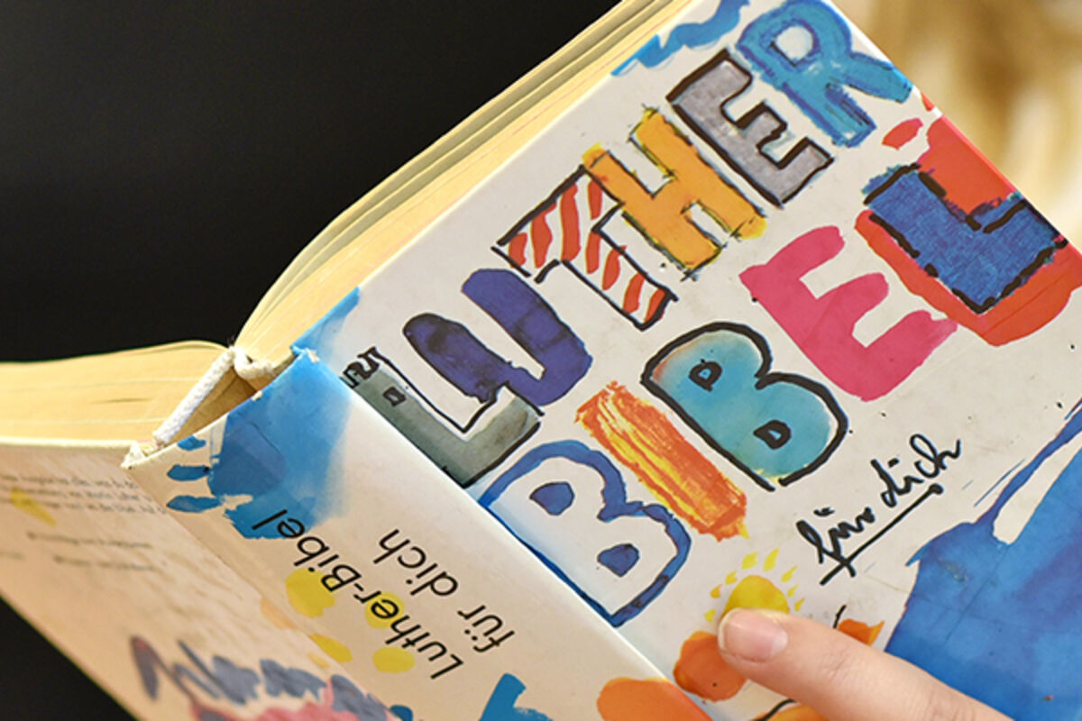 Jemand hält eine bunt aufgemachte Lutherbibel in den Händen