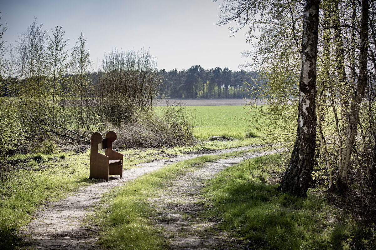 An einem Feldwegrand steht eine kleine Kirchenbank
