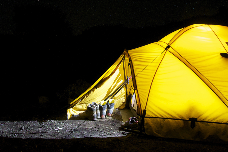 Ein von innen beleuchtetes Zelt bei Nacht.