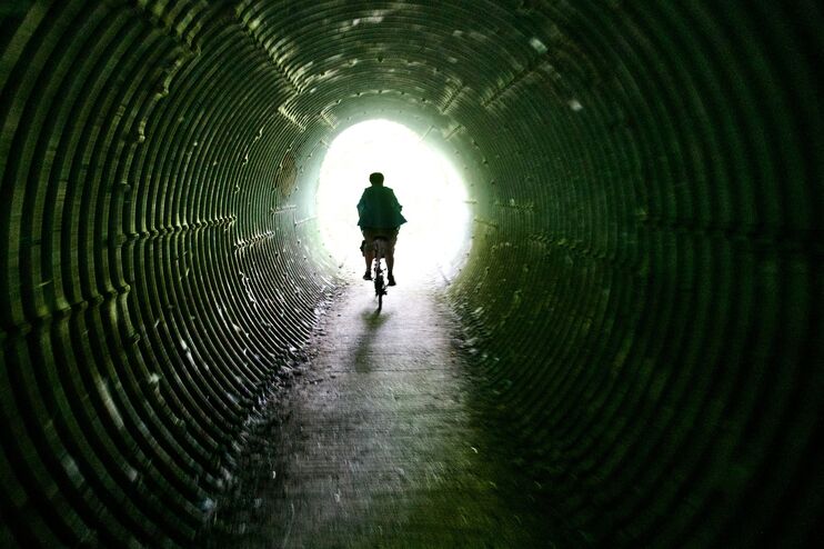 Ein Fahrradfahrer fährt auf das Licht am Ende eines Tunnels zu.
