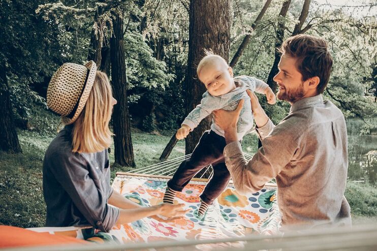 Eltern mit ihrem Kind in einem Park an einem See. 