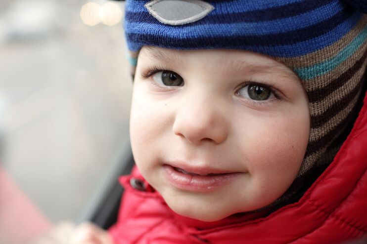 ein Kind in einem Bus steht am Fenster und schaut noch oben Richtung Kamera