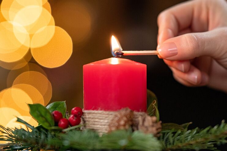 Ein Mensch zuendet eine Adventskerze an