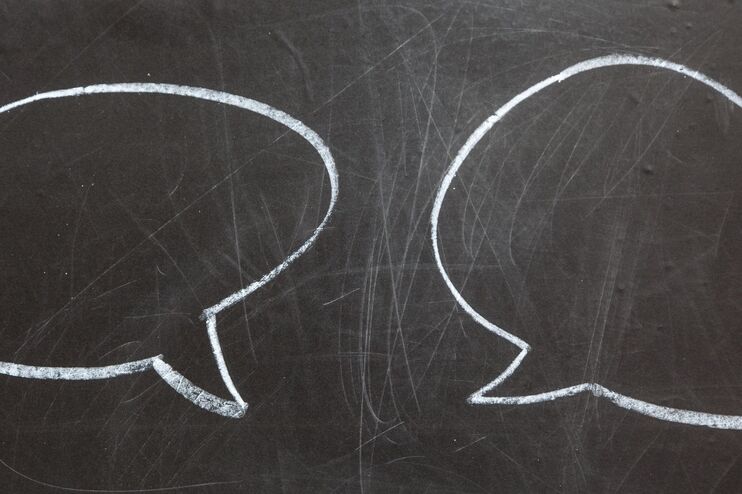 Auf einer Tafel sind mit weißer Kreide zwei Sprechblasen zu sehen.