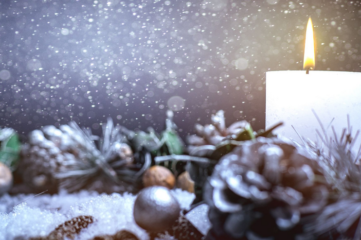 Eine weiße Kerze brennt in einem Adventsgeschenk.