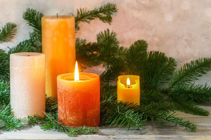 Ein Adventskranz mir vier orangefarbenen Kerzen, zwei davon brennen.