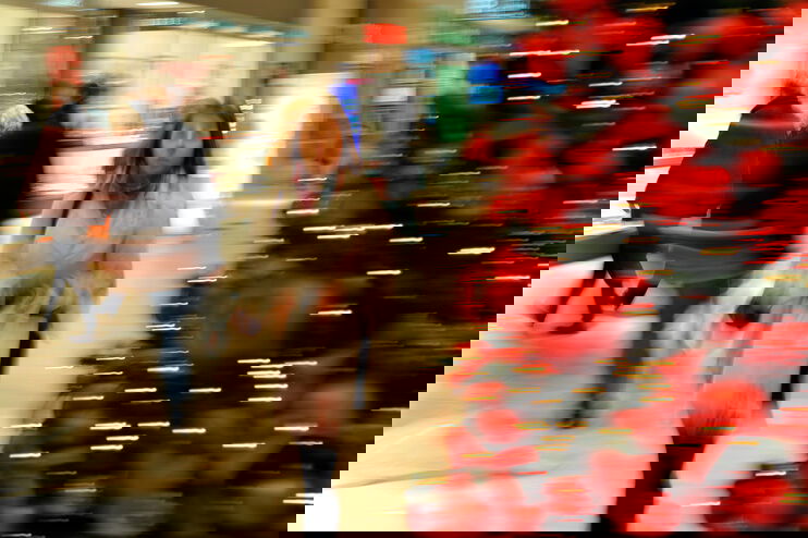 Eine als Frau lesbare Person geht an einem geschmückten Weihnachtsbaum vorbei.