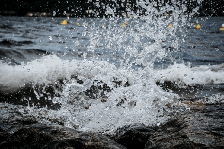 Wasser eines Flusses spritzt auf, als es auf Steine prallt.