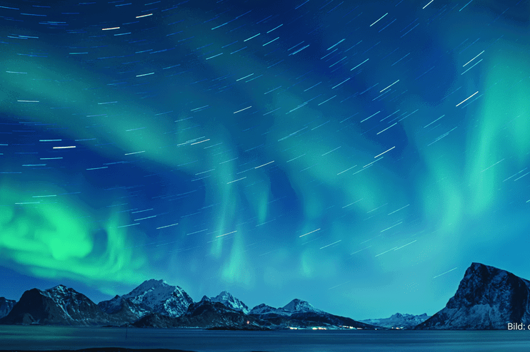 Über Bergen flackern in unterschiedlichen Grüntönen Polarlichter.