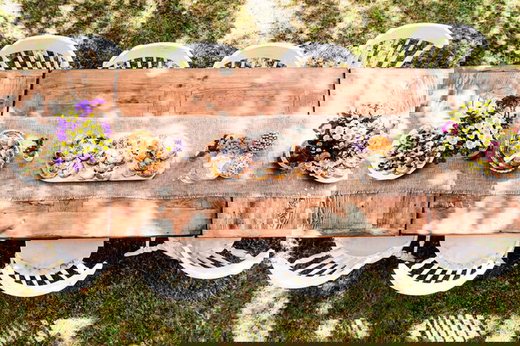 Eine langer gedeckter Tisch im Garten mit weißen Stühlen